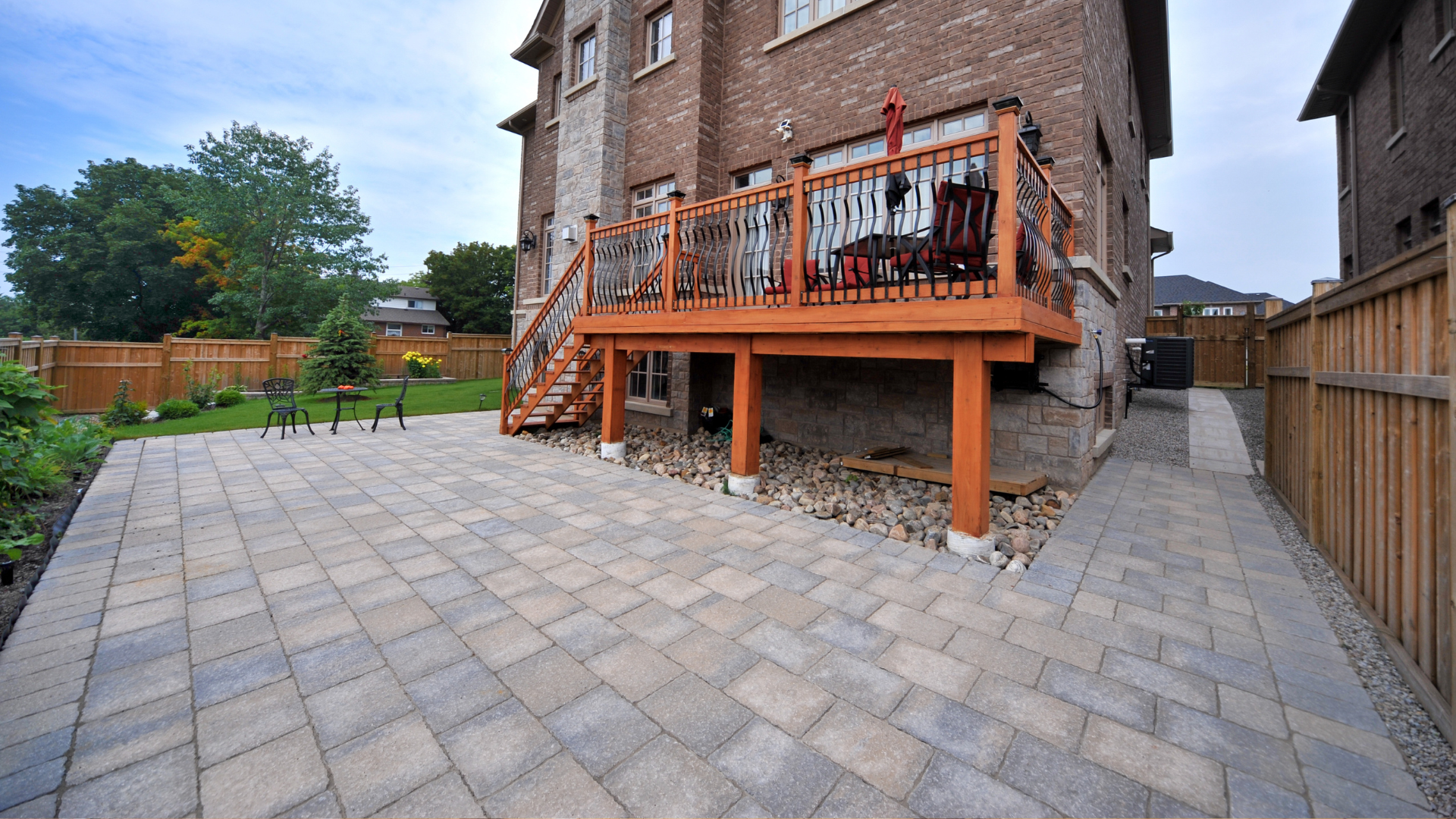 A brick patio with a wooden deck and railing